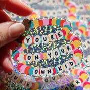 You're On Your Own Kid glitter sticker in hand